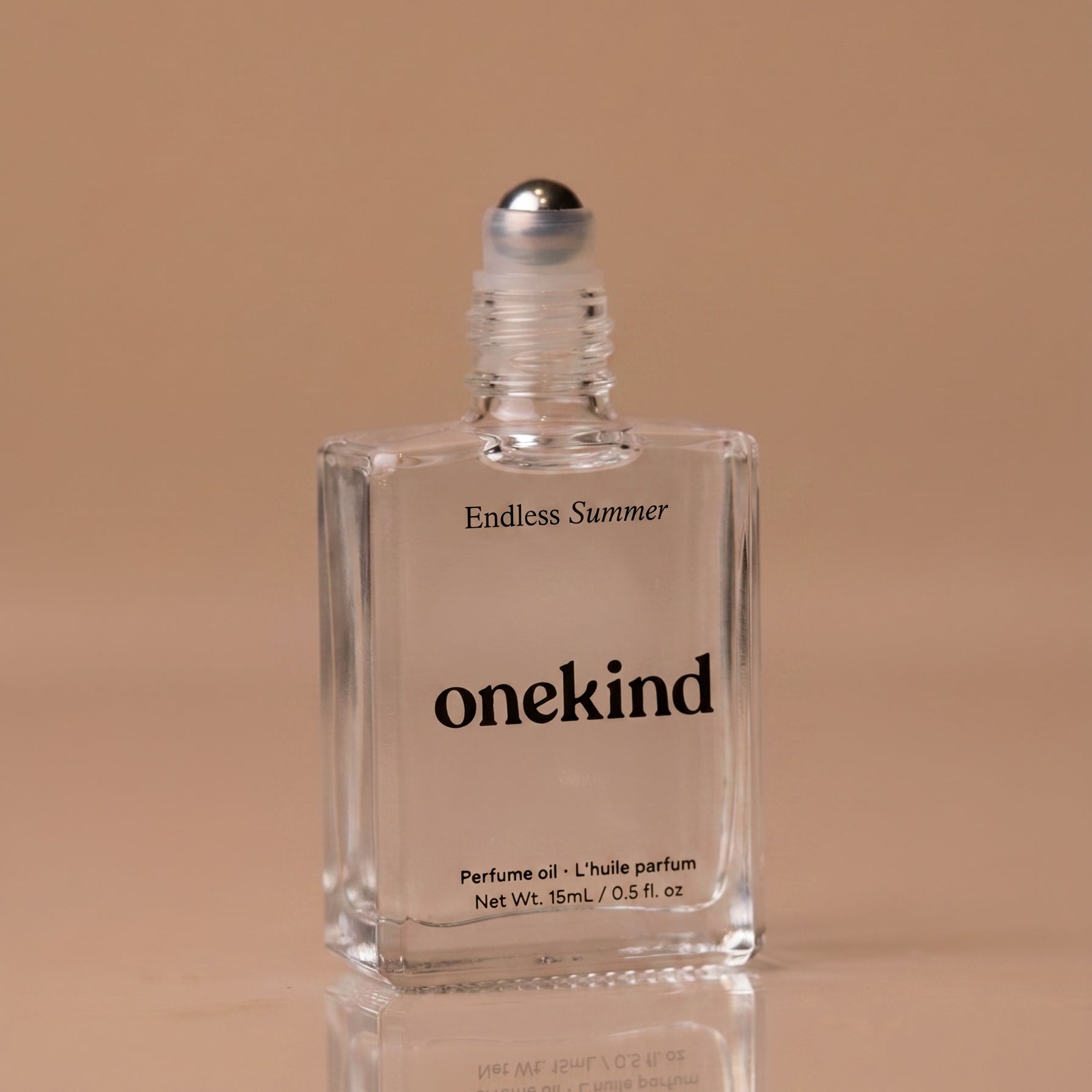 Clear bottle of 'Endless Summer' onekind perfume oil on a beige background