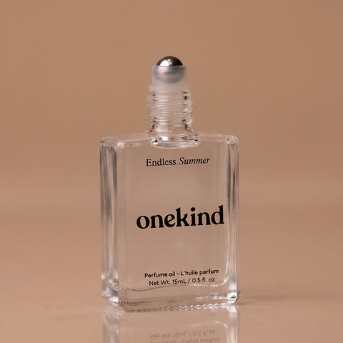 Clear bottle of 'Endless Summer' onekind perfume oil on a beige background