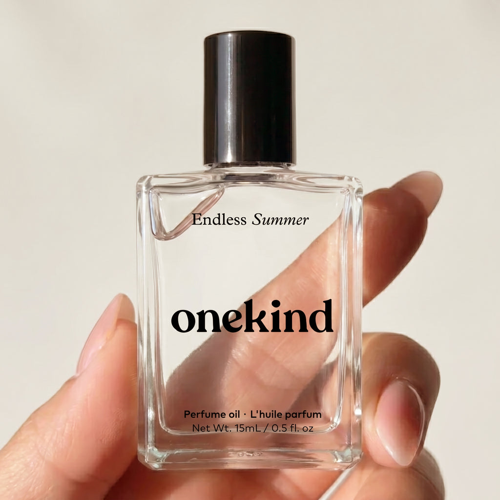 Onekind Endless Summer perfume oil bottle held by a hand against a neutral background